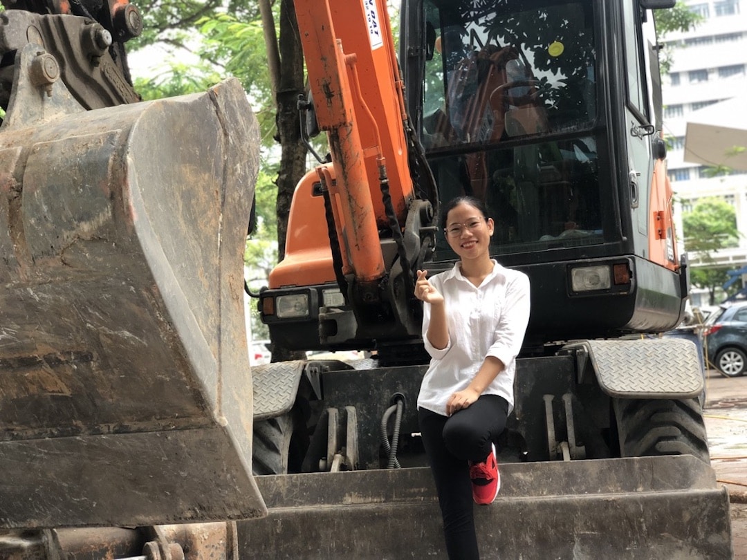 Young woman poses on digging machine
