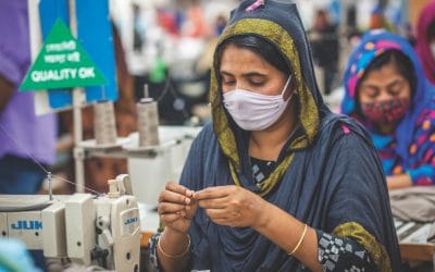 Woman wearing face mask works in garment factory