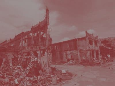 Red tinted photo of fallen buildings in disaster aftermath