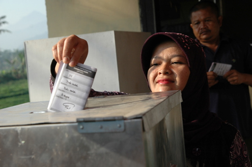 A woman inserts a ballot during Indonesia's elections
