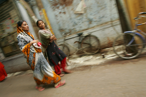 Women walk along a street in India. 